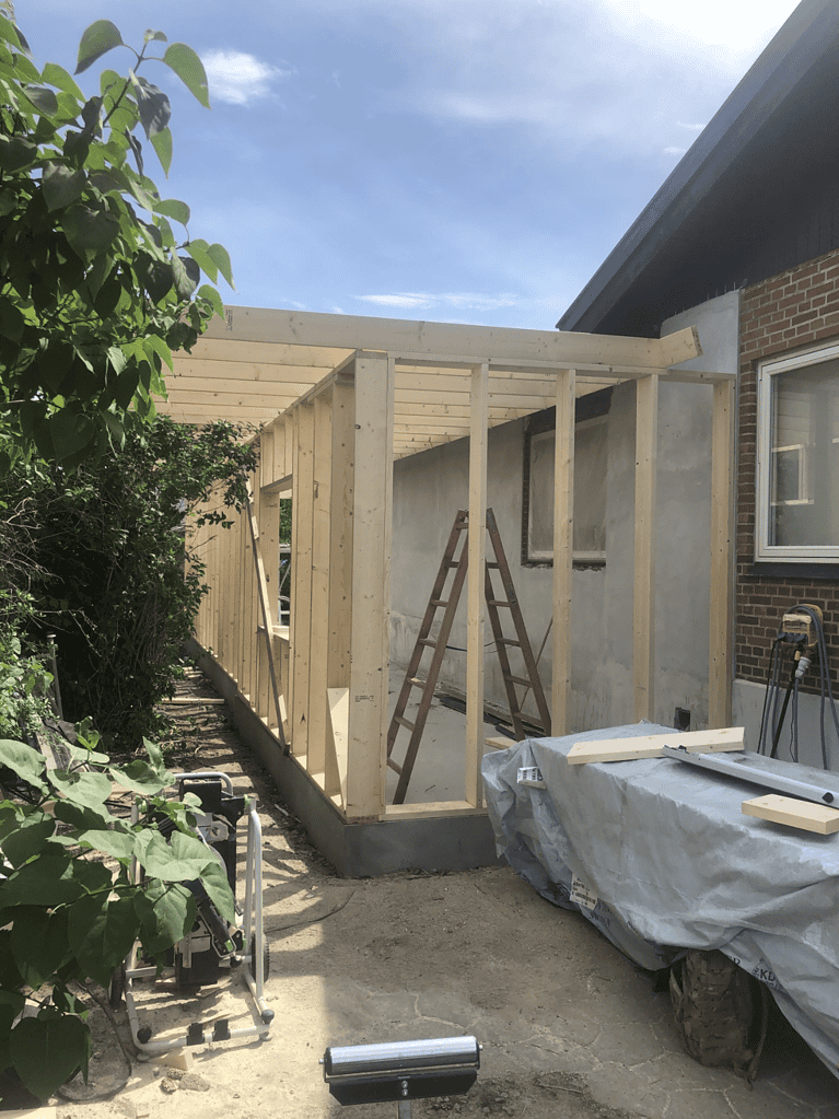 Træramme til tilbygning under opførelse ved hus.