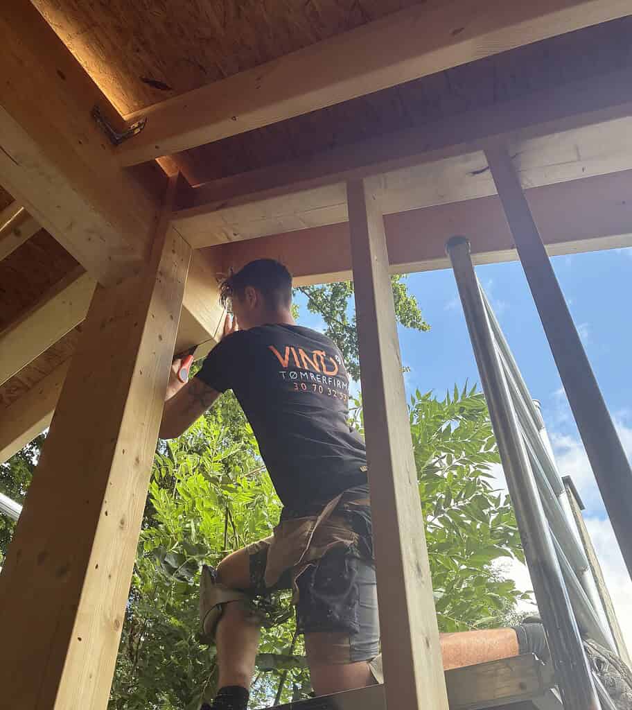 Tømrer saver i bjælke til ny tagkonstruktion